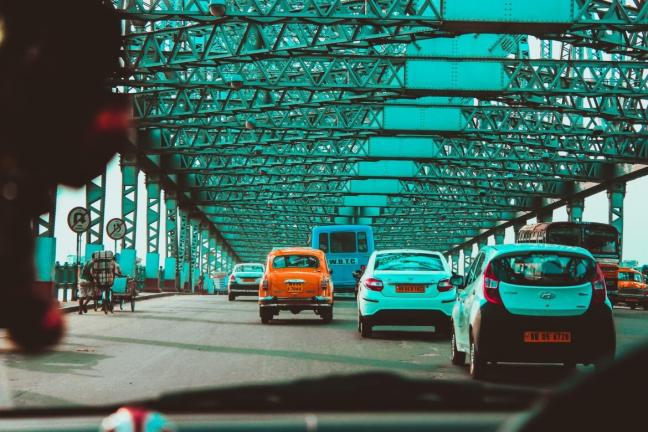 A road in Kolkata city with yellow taxis, transport corporation buses and cars.